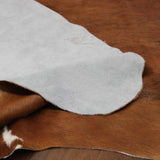 Backside of brown and white Texas Range cowhide rug displaying durable leather.