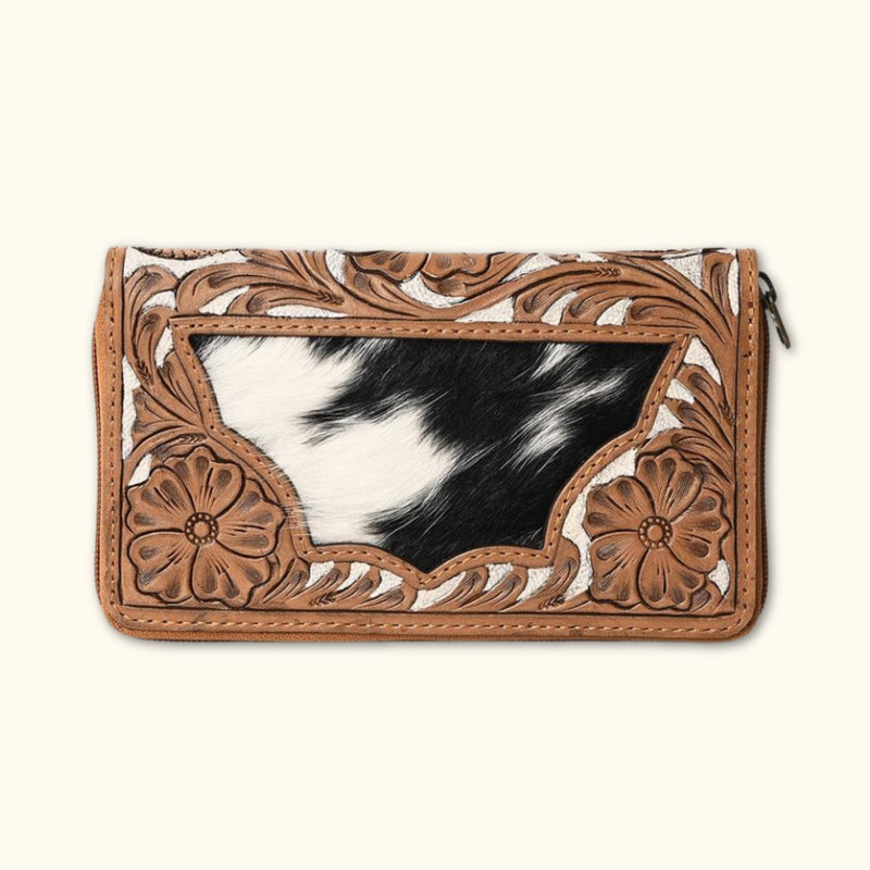 Front view of a Western-style hair-on cowhide zip clutch with intricate floral tooling.