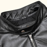 Close-up of the collar and zipper details of a black leather jacket.