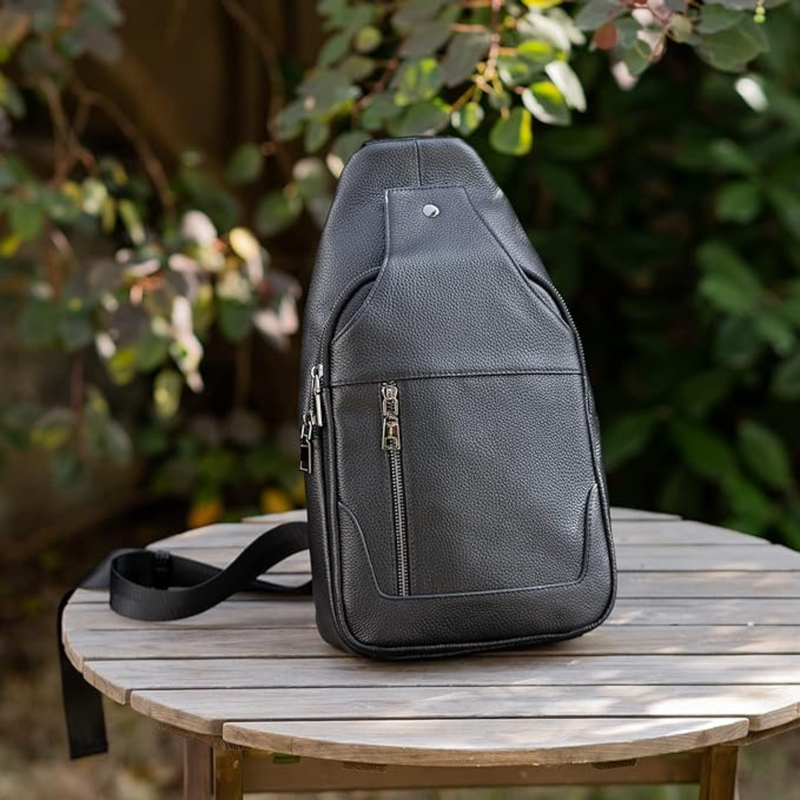 Western Adventure Leather Sling Bag placed on a wooden table outdoors, with greenery in the background.