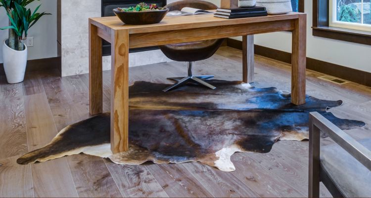 Mobile view of a luxurious cowhide rug collection banner featuring a premium cowhide rug under a wooden desk in a modern home setting