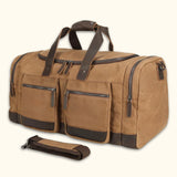 Close-up of The Weekender - Waxed Canvas Leather Duffel bag, showcasing its front pockets, sturdy zippers, and included shoulder strap, highlighting its practical and durable design.