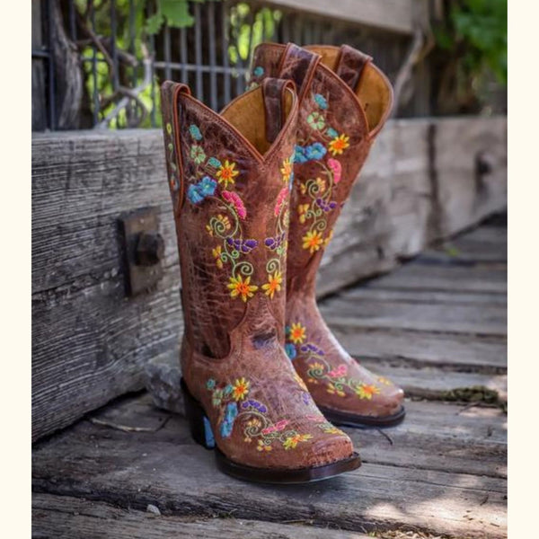 Wildflower Bliss Leather Cowgirl Boots placed on a wooden deck, emphasizing the floral embroidery and handcrafted leather design.